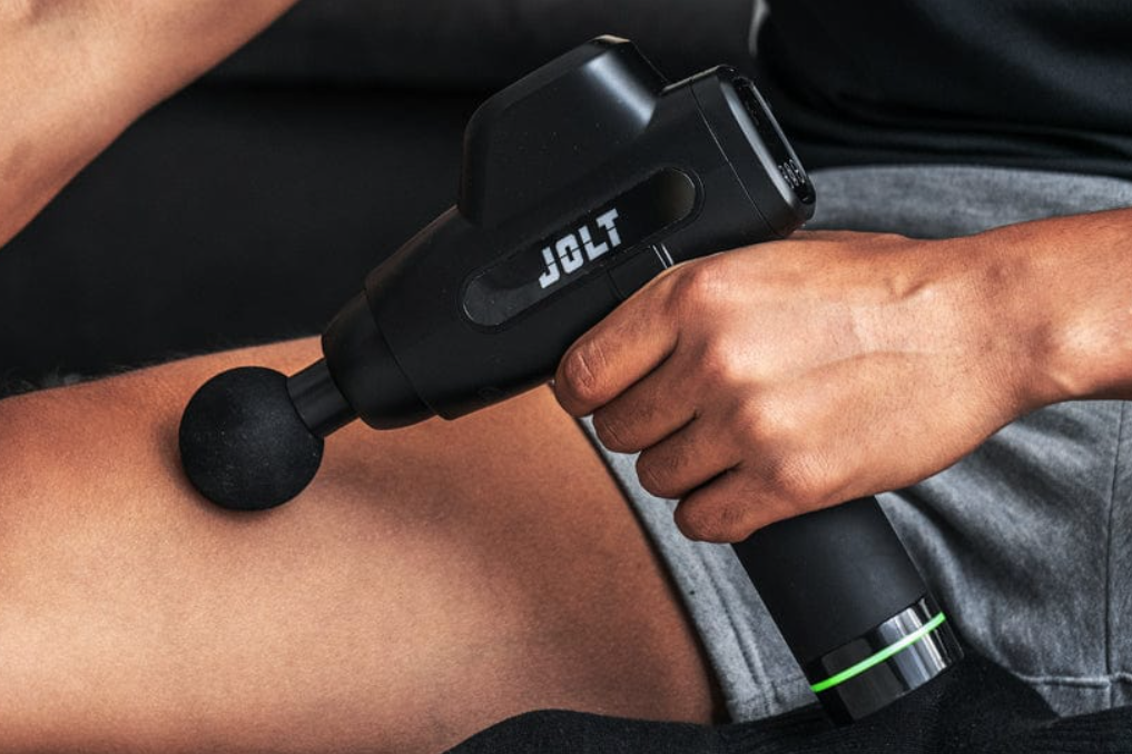 Utilisateur testant la puissance pistolet de massage sur sa cuisse après le sport