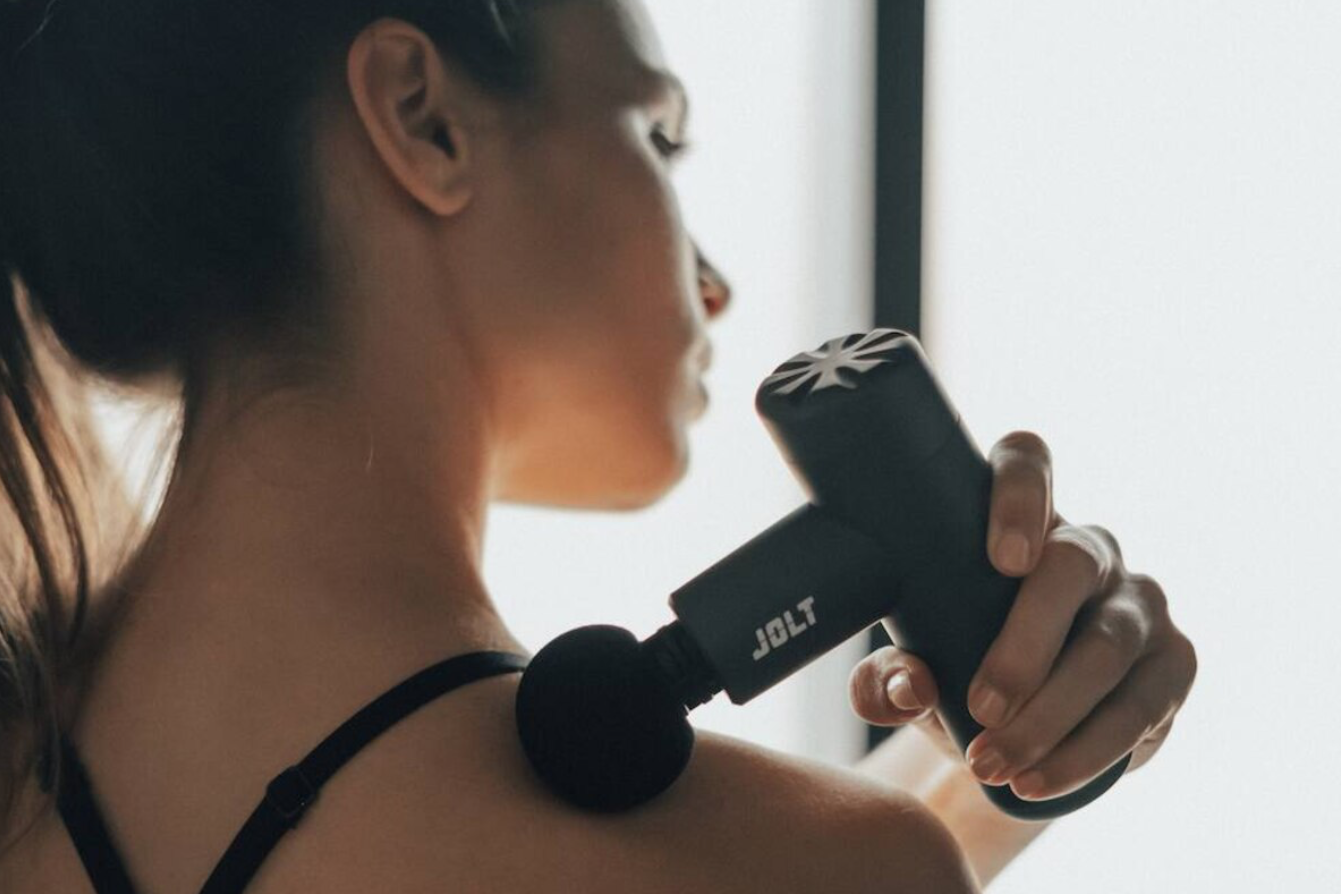 Sportif utilisant un pistolet de massage pour soulager ses tensions musculaires