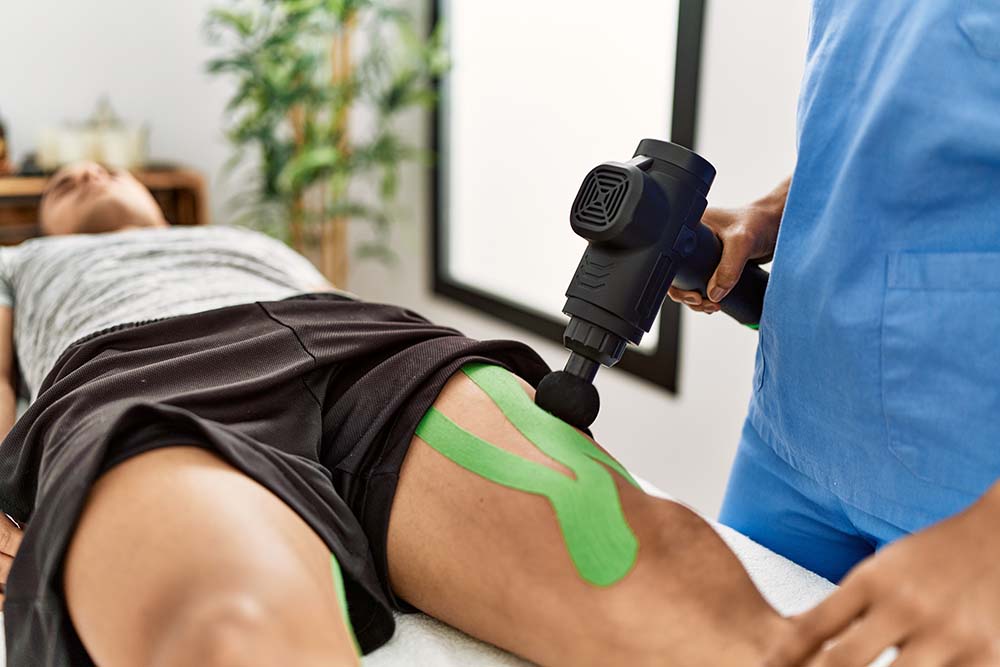 Massage ciblé d’un muscle mis en évidence avec un pistolet de massage à percussion