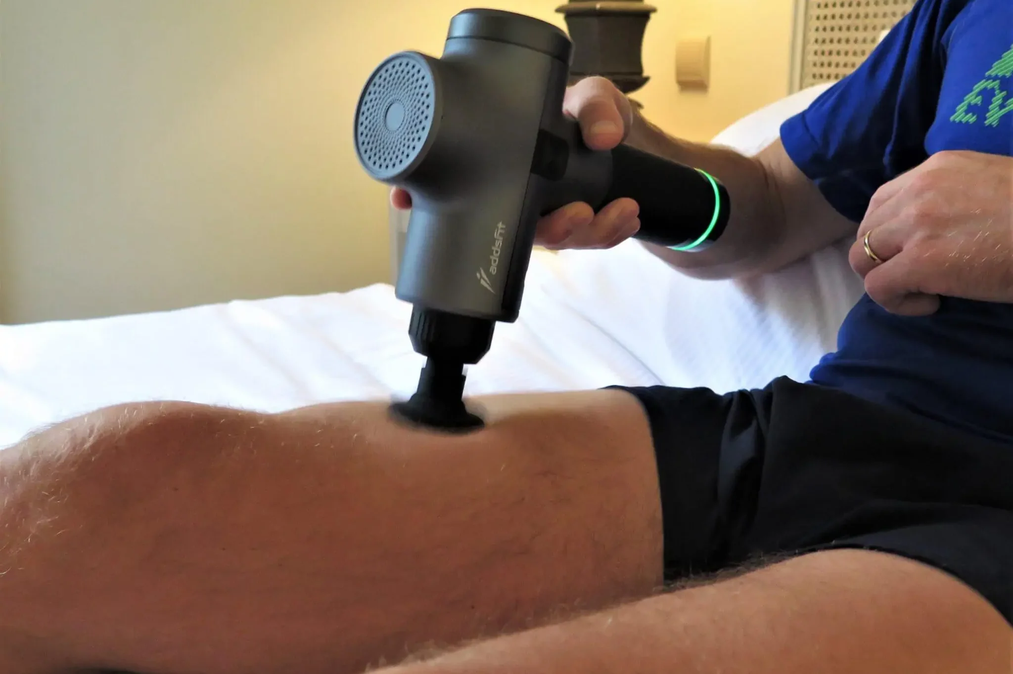 Personne utilisant un pistolet de massage sur sa cuisse pour détendre les quadriceps après le sport