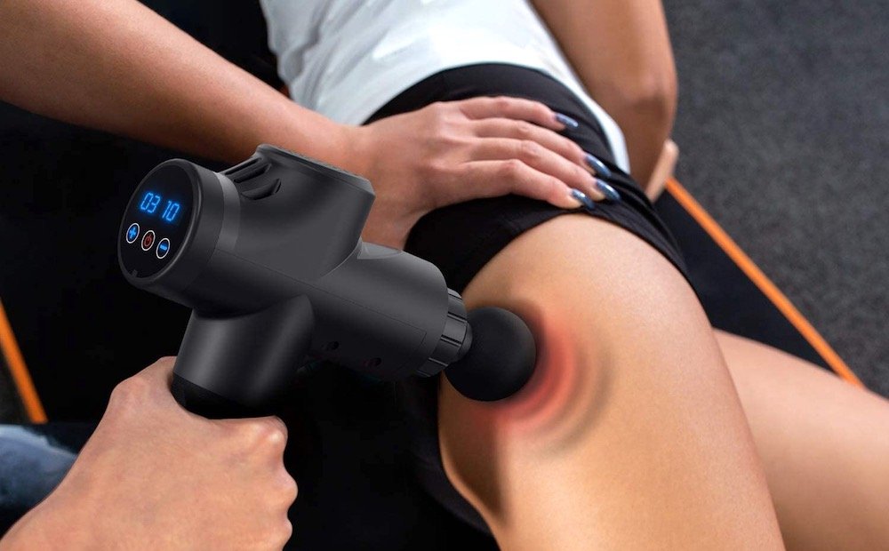 Massage ciblé du vaste latéral avec un pistolet de massage, zone sensible mise en évidence en rouge