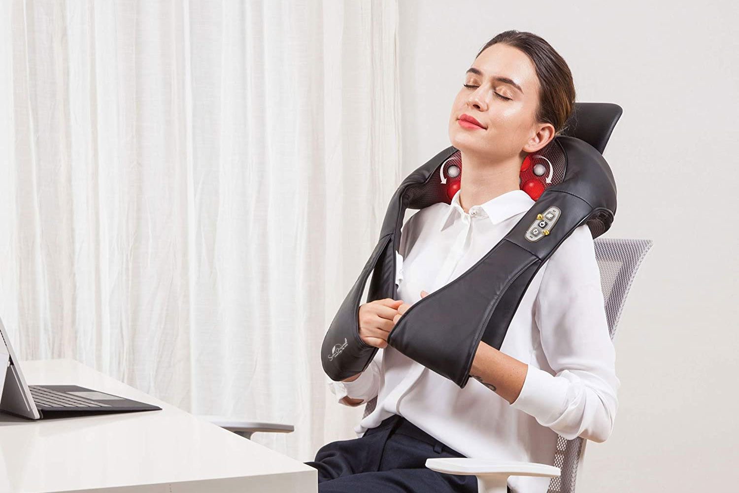Femme détendue avec un masseur électrique sur la nuque, assise sur un siège de bureau