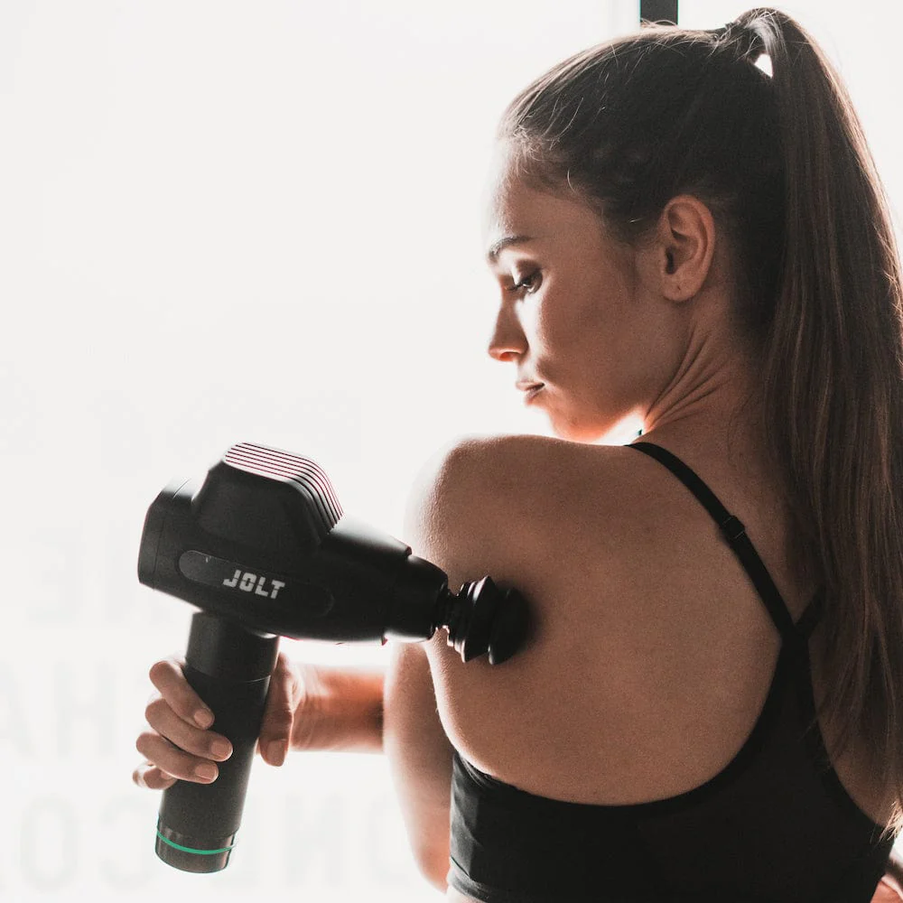 Sportif comparant un pistolet de massage ou balle de massage après l'entraînement